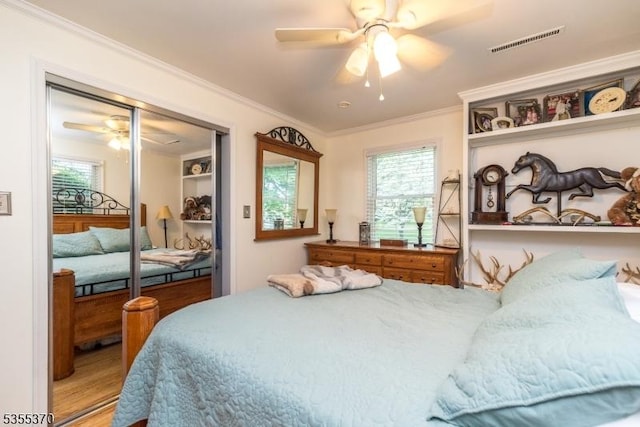 bedroom featuring crown molding, wood finished floors, a ceiling fan, and a closet