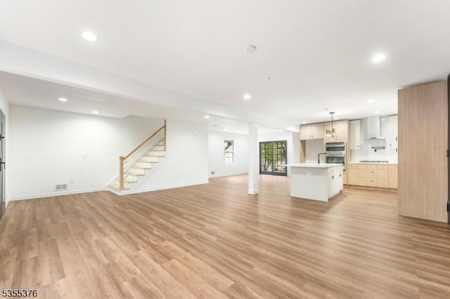 unfurnished living room featuring recessed lighting, baseboards, light wood-type flooring, visible vents, and stairway