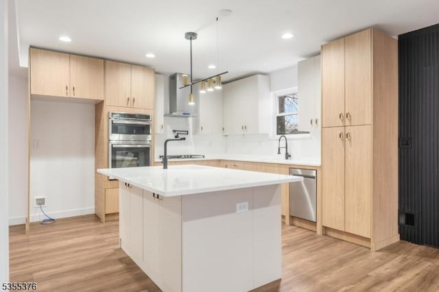 kitchen with appliances with stainless steel finishes, light wood-style flooring, wall chimney exhaust hood, and light brown cabinets