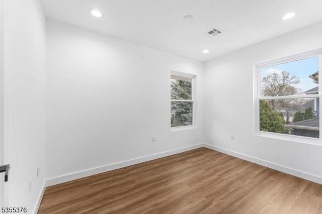 empty room with baseboards, recessed lighting, wood finished floors, and visible vents