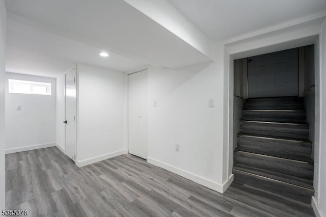 below grade area with recessed lighting, baseboards, wood finished floors, and stairway