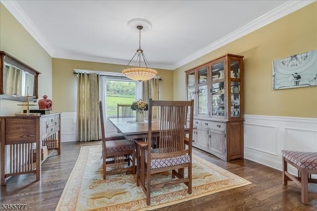 dining room with ornamental molding, wood finished floors, a wainscoted wall, and a decorative wall