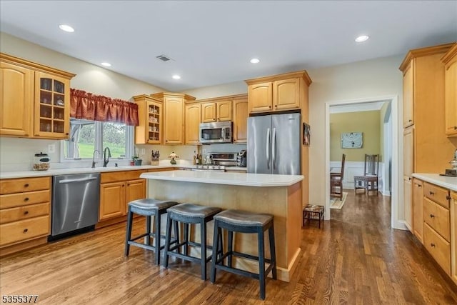 kitchen with stainless steel appliances, a kitchen breakfast bar, a center island, light countertops, and recessed lighting