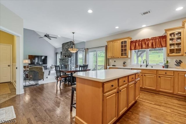kitchen with light countertops, a kitchen island, a sink, plenty of natural light, and lofted ceiling