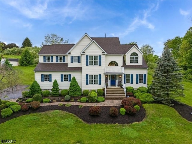 traditional home featuring a front yard and roof with shingles