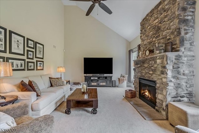 carpeted living room featuring high vaulted ceiling, a ceiling fan, and a stone fireplace