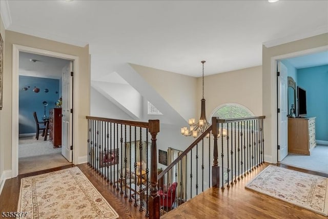 hallway with a chandelier, an upstairs landing, wood finished floors, and baseboards