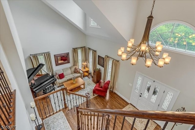 living room with high vaulted ceiling, a chandelier, wood finished floors, and baseboards
