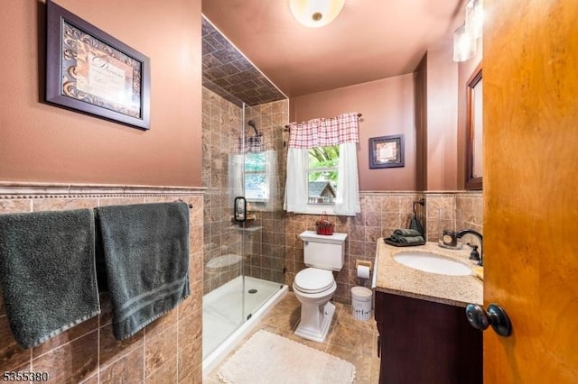 bathroom featuring vanity, toilet, tile patterned floors, tile walls, and a stall shower