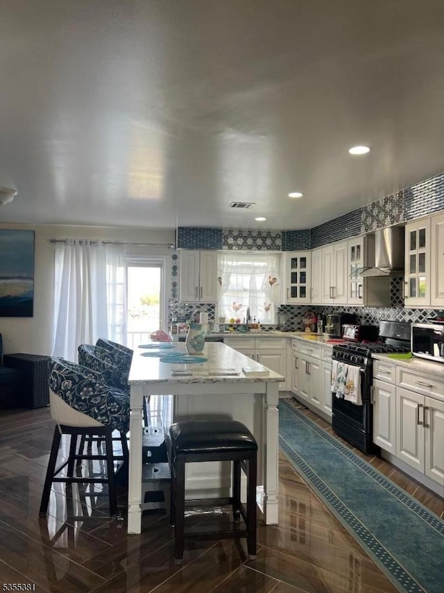 3 Harbor Front Ct Unit 3, Elizabeth City, NJ 07206 - kitchen featuring black range with gas cooktop, wall chimney range hood, healthy amount of natural light, white cabinetry, and recessed lighting