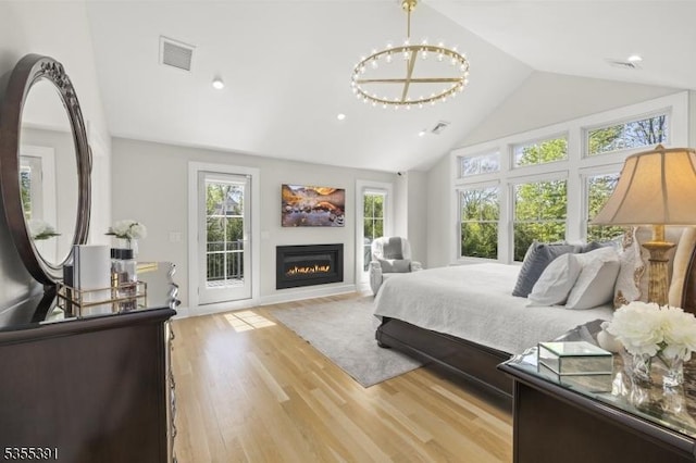bedroom with an inviting chandelier, access to exterior, visible vents, high vaulted ceiling, and a glass covered fireplace