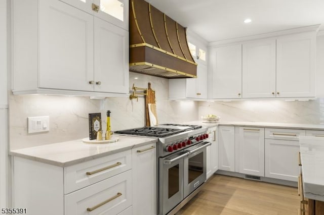 kitchen with white cabinets, backsplash, custom range hood, and range with two ovens