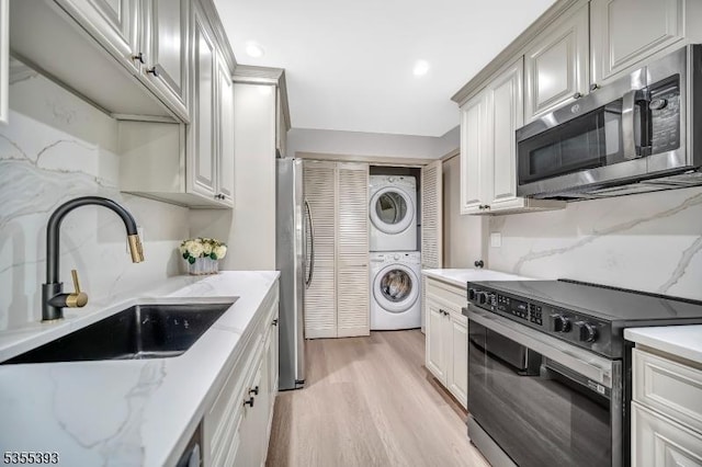 42B Catalpa Plz Unit B, Monroe Twp, NJ 08831 - kitchen with stainless steel appliances, stacked washer / dryer, a sink, decorative backsplash, and light wood-style floors