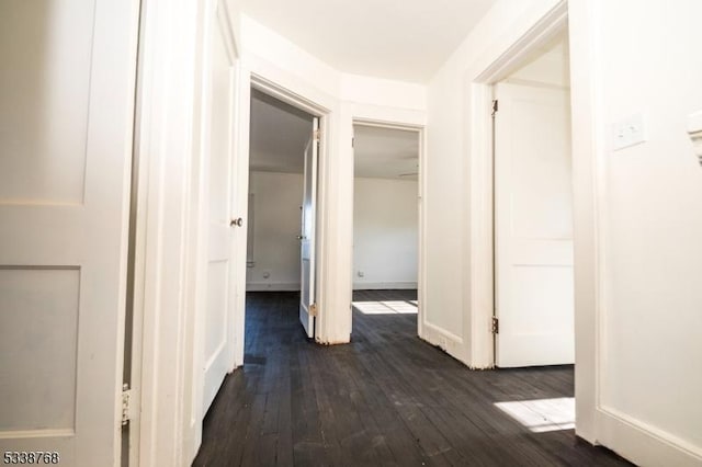 hallway featuring baseboards and dark wood finished floors