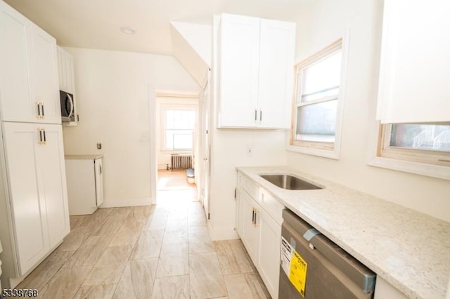 kitchen featuring radiator heating unit, appliances with stainless steel finishes, light stone countertops, and white cabinetry