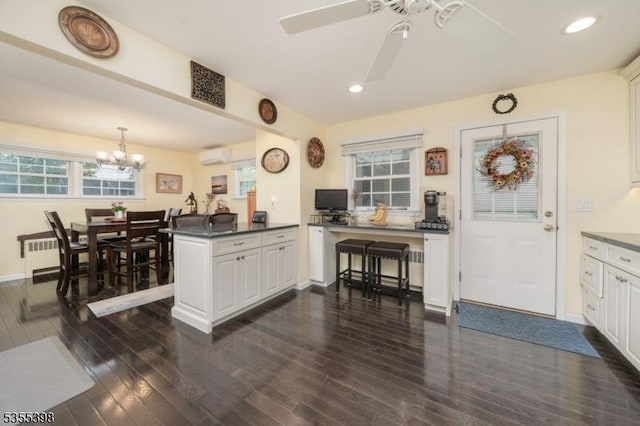 kitchen featuring an AC wall unit, dark wood finished floors, a ceiling fan, dark countertops, and recessed lighting