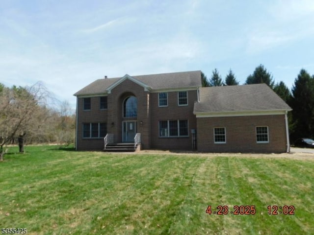 colonial home with brick siding and a front yard