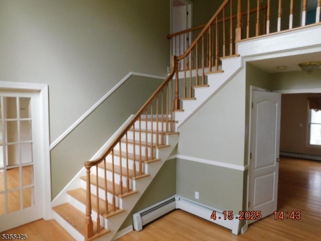 stairs with a baseboard radiator, baseboard heating, and wood finished floors