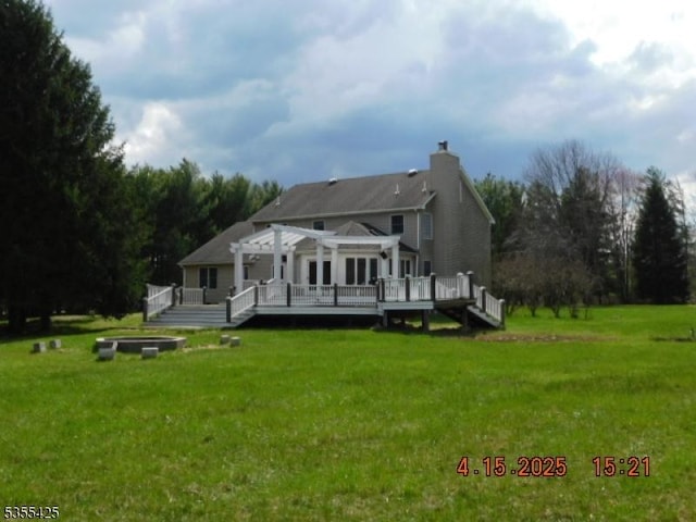 back of property featuring a lawn, a chimney, a pergola, and a deck