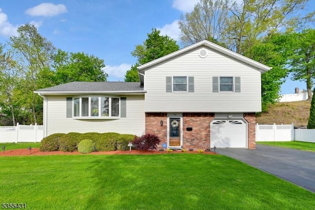 tri-level home with driveway, an attached garage, and brick siding