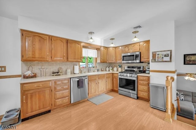 kitchen featuring appliances with stainless steel finishes, light wood-type flooring, tasteful backsplash, light countertops, and vaulted ceiling