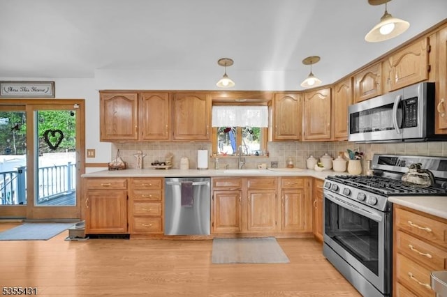 kitchen with stainless steel appliances, a sink, light countertops, and decorative backsplash