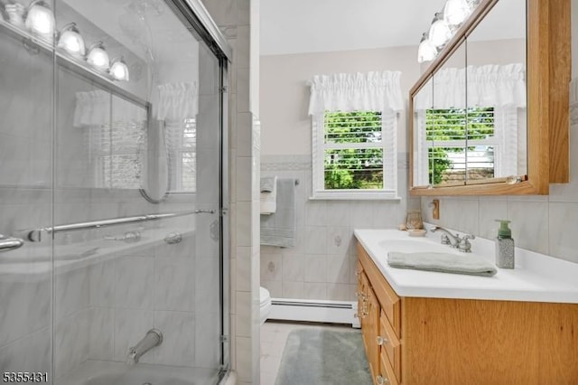 full bath with a baseboard heating unit, vanity, combined bath / shower with glass door, tile walls, and toilet