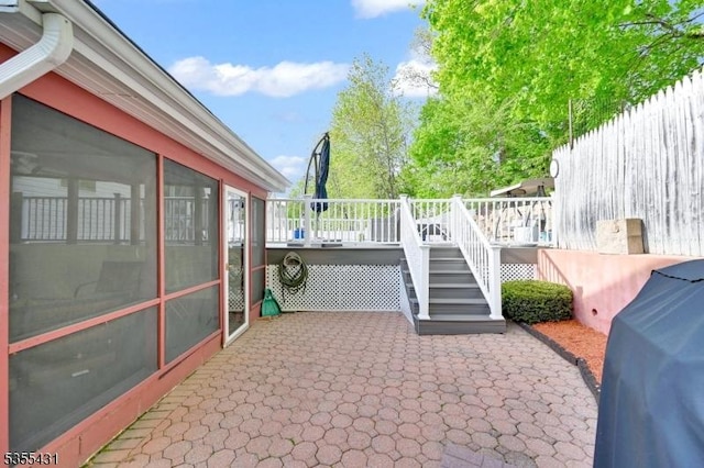 view of patio with a wooden deck, stairs, a sunroom, and grilling area
