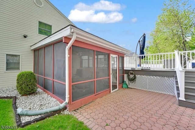 view of property exterior with a sunroom, a deck, and a patio