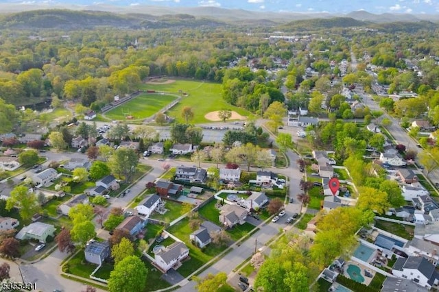 aerial view of property's location featuring nearby suburban area, a forest, and mountains