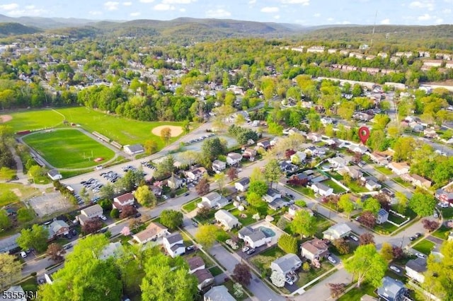 view of property location featuring mountains, a heavily wooded area, and nearby suburban area