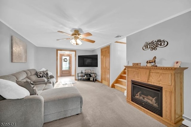 living room with a glass covered fireplace, ceiling fan, light colored carpet, crown molding, and baseboards