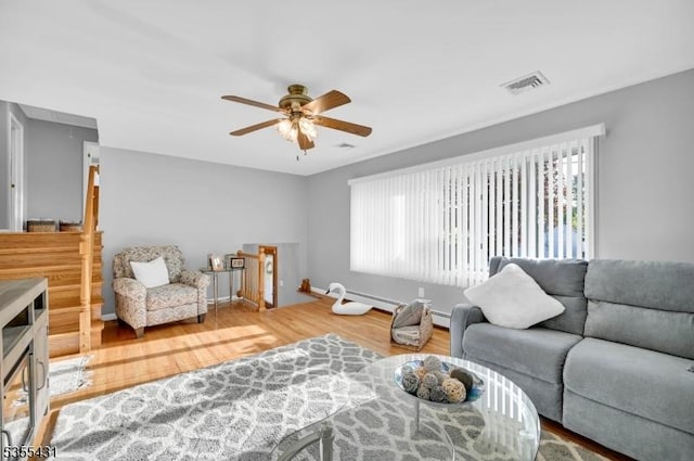 living area with attic access, a ceiling fan, and wood finished floors