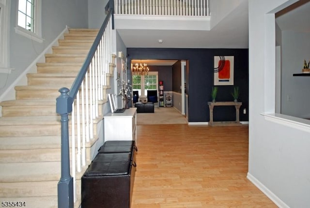 foyer entrance with stairs, wood finished floors, a chandelier, and baseboards
