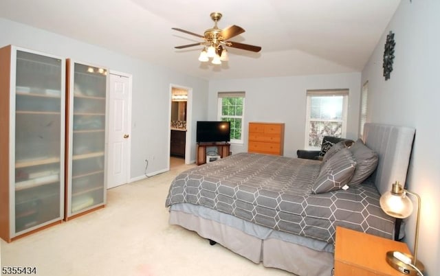 bedroom featuring light colored carpet, lofted ceiling, connected bathroom, ceiling fan, and baseboards