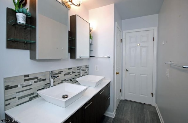 full bathroom featuring backsplash, baseboards, wood finished floors, and double vanity