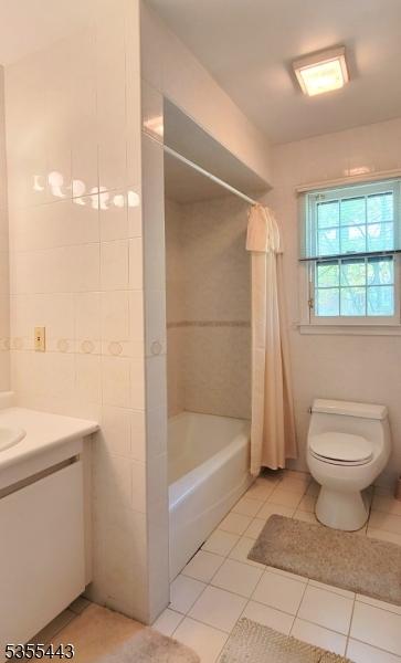 bathroom featuring tile patterned floors, toilet, vanity, and shower / bath combination with curtain