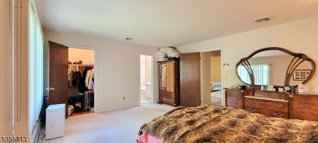 bedroom with carpet flooring, a spacious closet, a closet, and ensuite bathroom