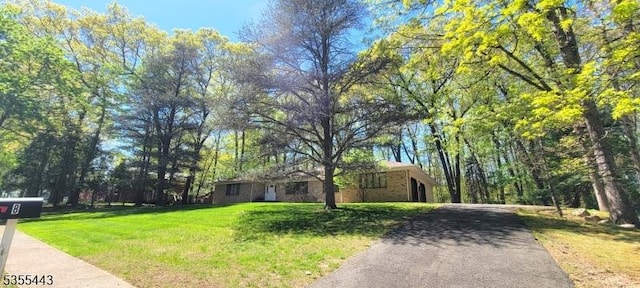 view of front of property with asphalt driveway and a front yard