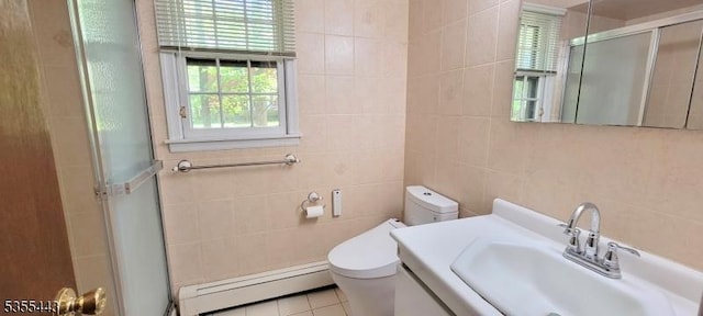 full bathroom with baseboard heating, tile walls, a shower with shower door, toilet, and tile patterned flooring