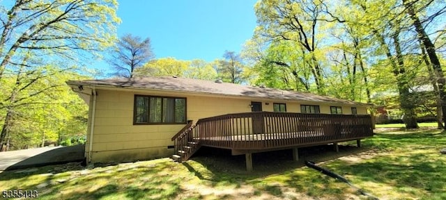 rear view of house featuring a deck and a yard