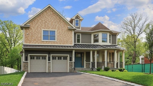 view of front of house featuring a standing seam roof, a porch, asphalt driveway, a garage, and metal roof