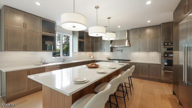 kitchen featuring wall chimney exhaust hood, light wood-style flooring, decorative backsplash, and recessed lighting