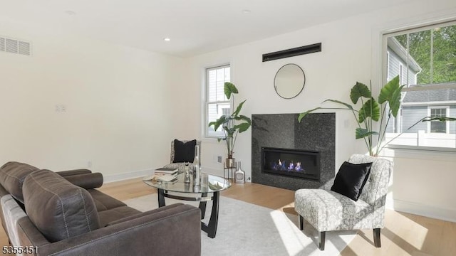 living area with wood finished floors, a tiled fireplace, and baseboards