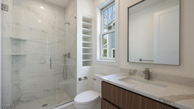 full bath with toilet, plenty of natural light, a marble finish shower, and vanity