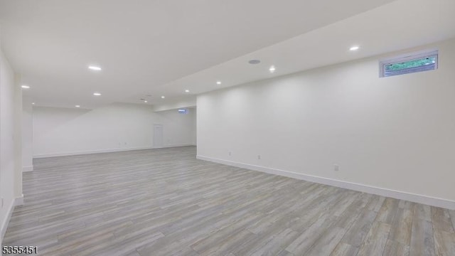 finished below grade area featuring light wood finished floors, recessed lighting, and baseboards