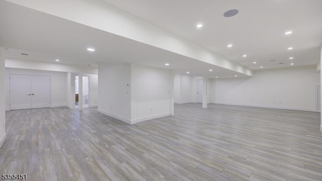 finished below grade area featuring light wood-type flooring, baseboards, and recessed lighting