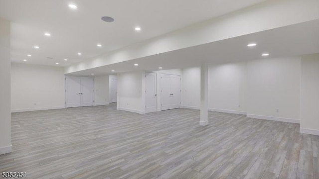 finished below grade area featuring light wood finished floors, baseboards, and recessed lighting