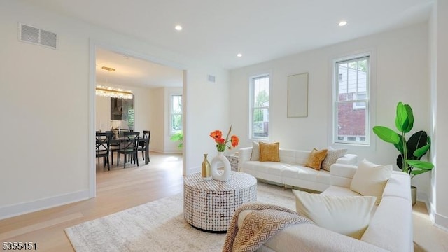 living area featuring light wood-style floors, recessed lighting, baseboards, and a chandelier