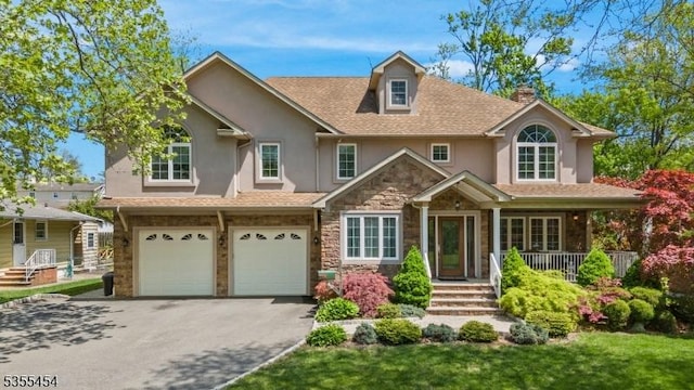 view of front of house with an attached garage, aphalt driveway, stone siding, stucco siding, and a porch